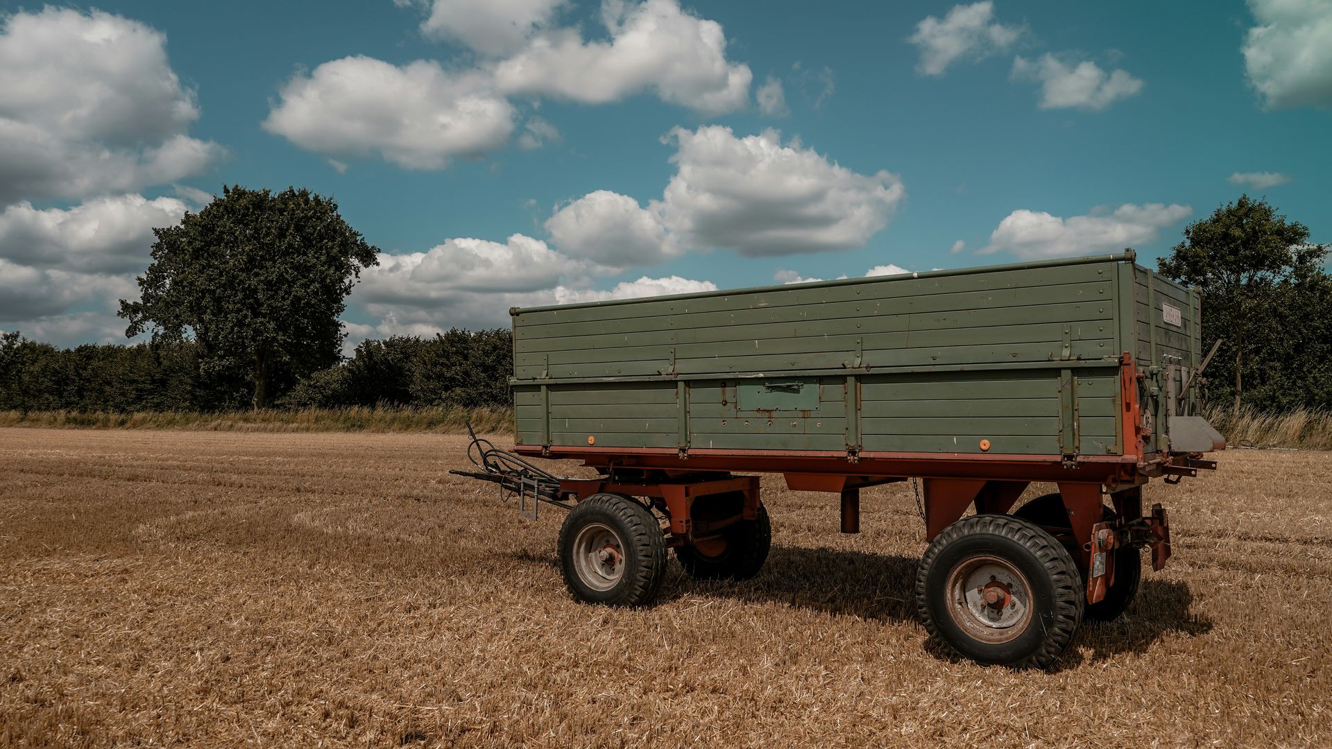 Farm trailer parked in a golden field under blue sky.
